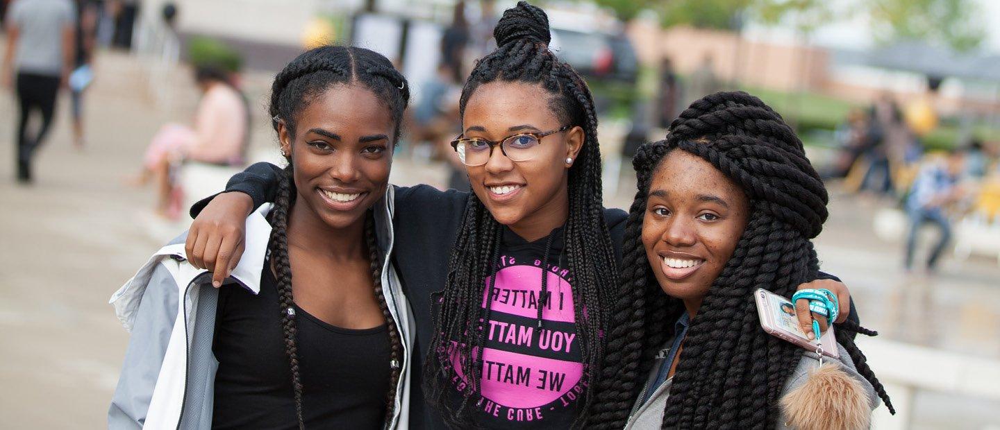 three women with their arms around each other, posing for a photo