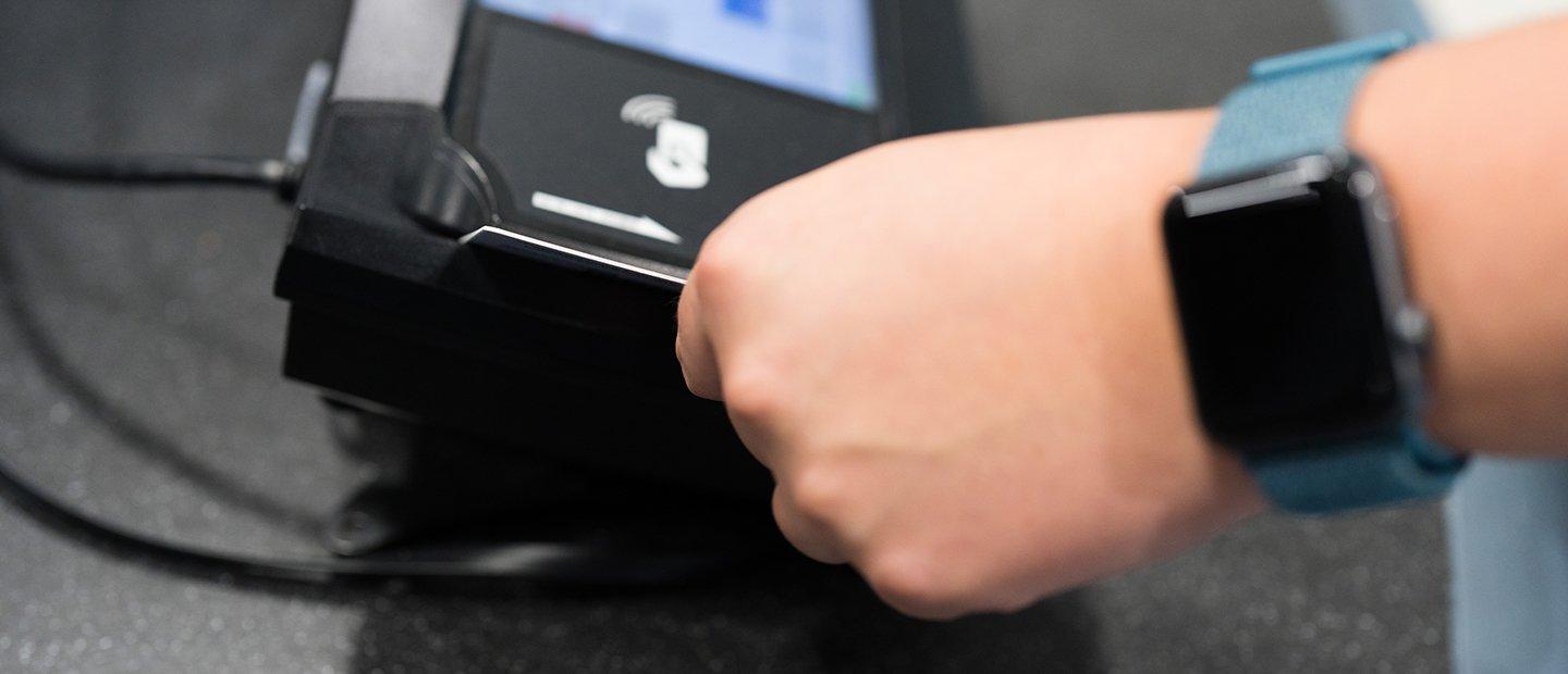 A hand swiping a card through a card reader.